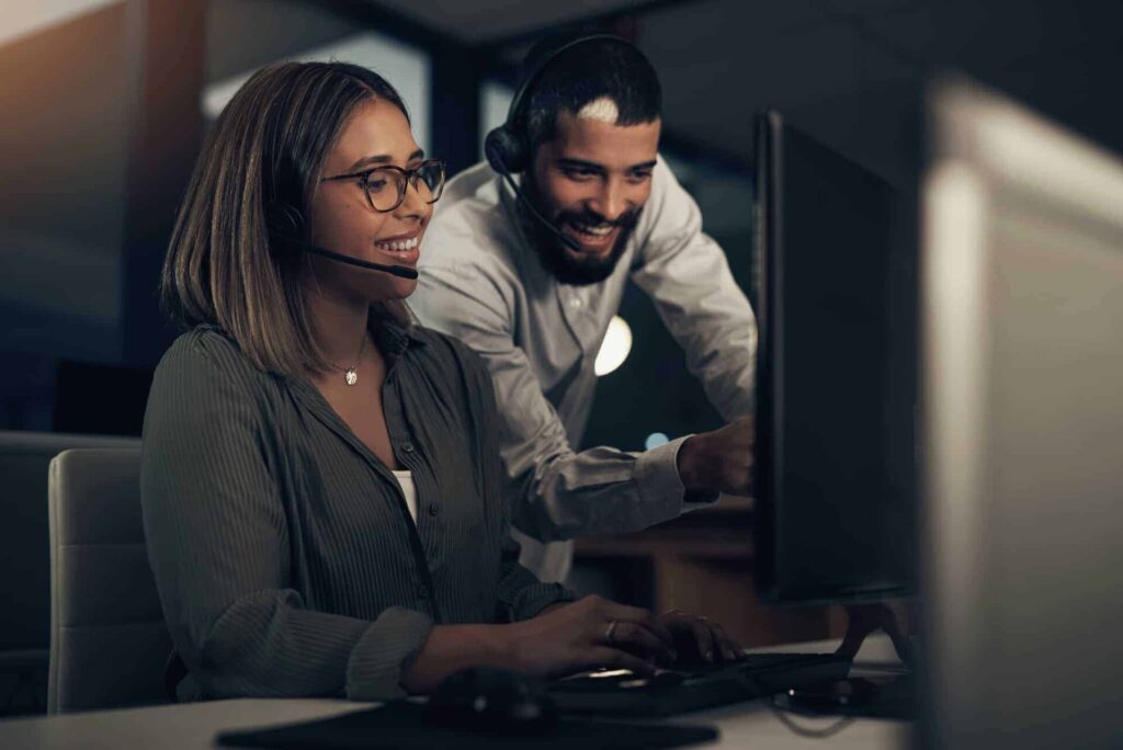 shot of two call centre agents working together in an office at night.jpg